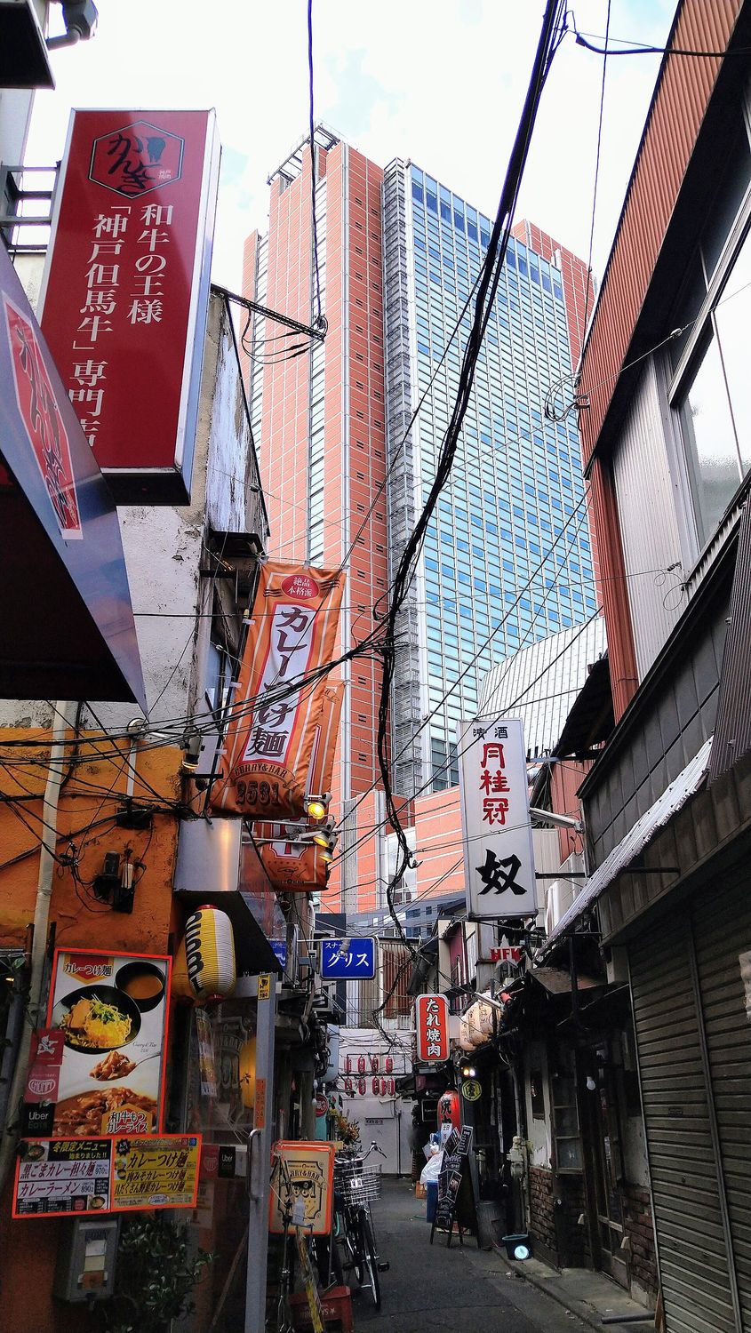 A narrow alley of small bars in Sangenjaya with Carrot Tower rising behind it, Setagaya, Tokyo